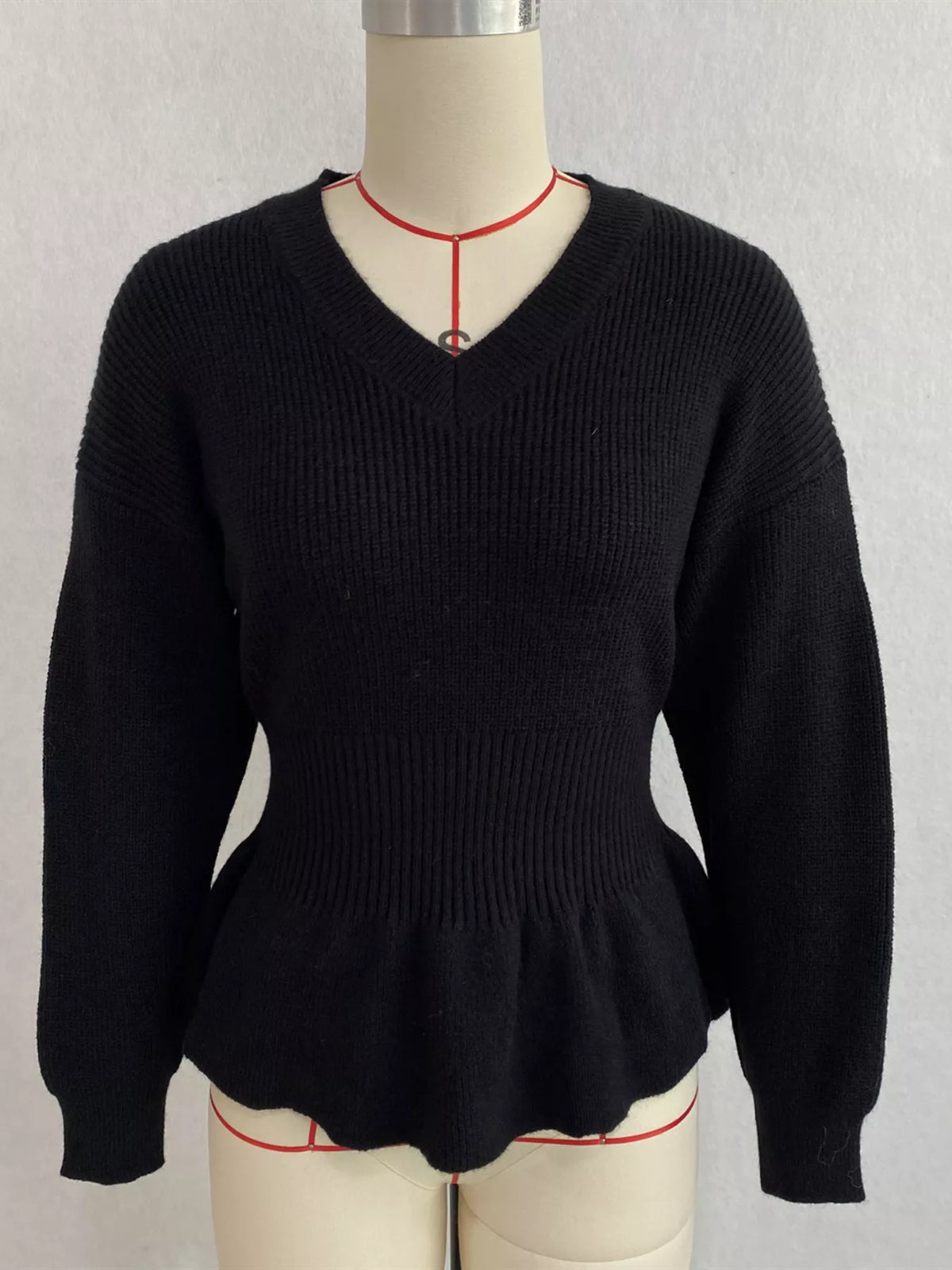 Black v-neck peplum-hem knit sweater, front on dress form.