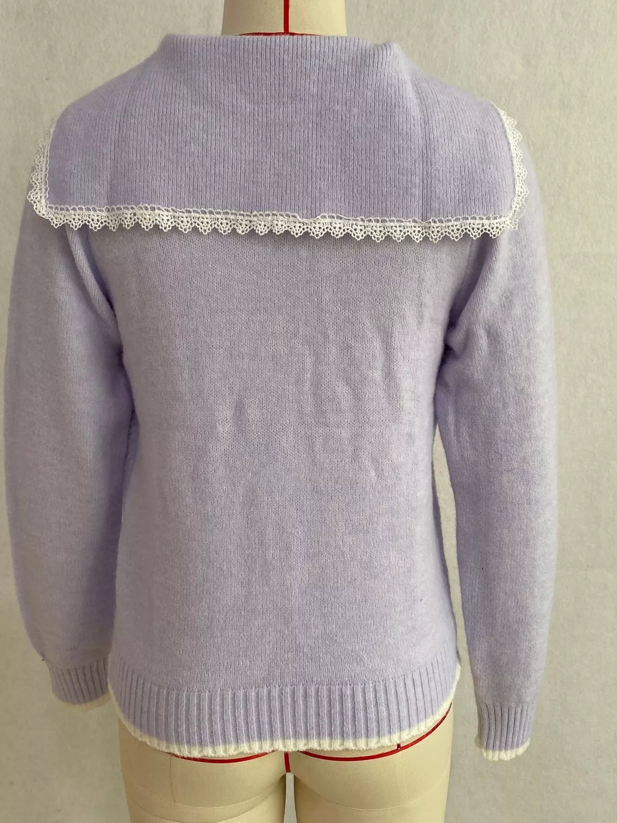 Lavender cable-knit cardigan with lace trim, back on dress form.