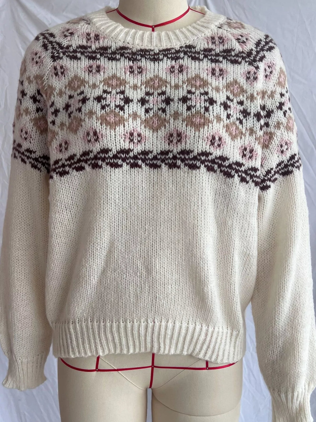 Cream fair isle round-neck sweater, front on dress form.