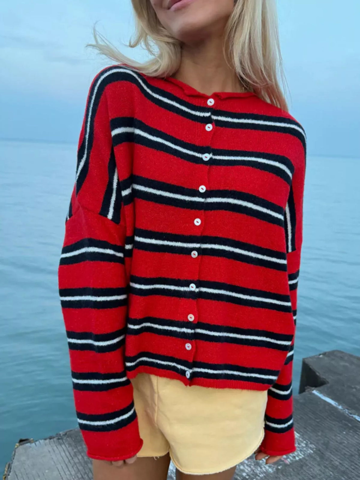 Red and black striped button-front cardigan, front view by the sea