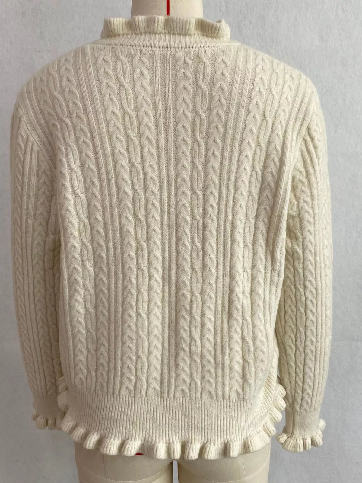 Ivory cable-knit ruffle-trim cardigan, back on dress form.