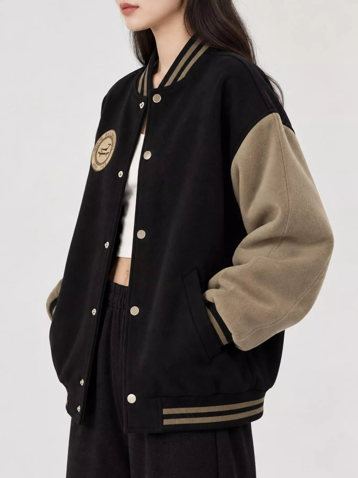 Black and beige color-block varsity bomber jacket, side view