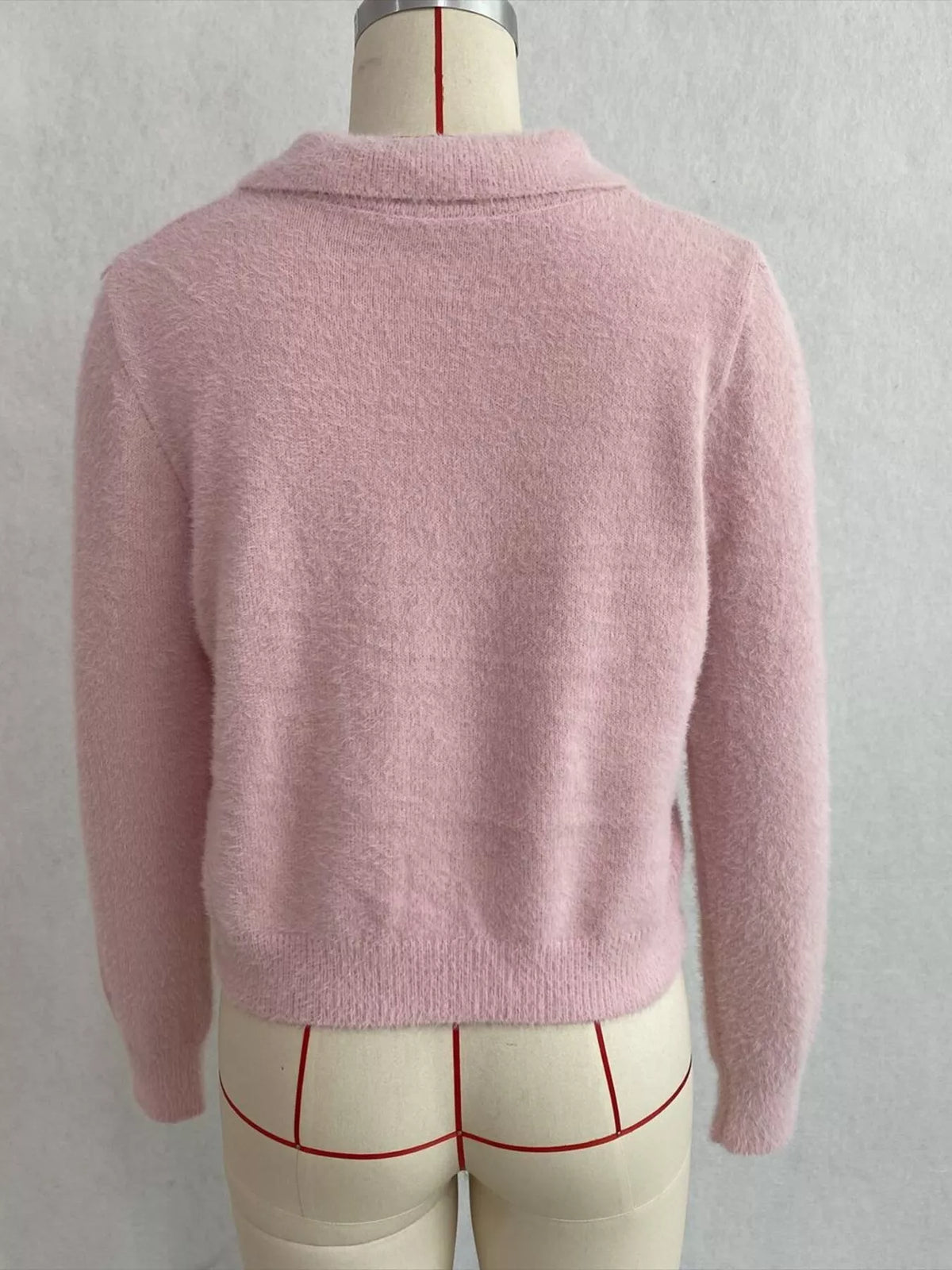 Pink fuzzy letter zip-up cardigan, back on dress form.