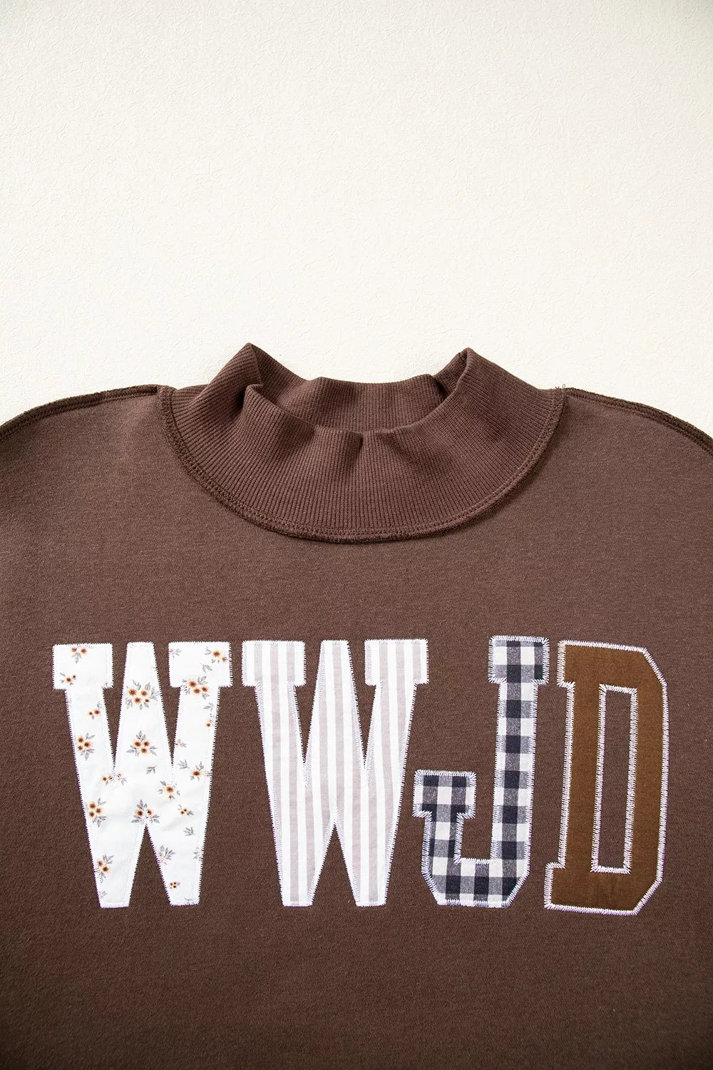 Brown wwjd patchwork graphic mock-neck sweatshirt, mock neck and lettering detail.