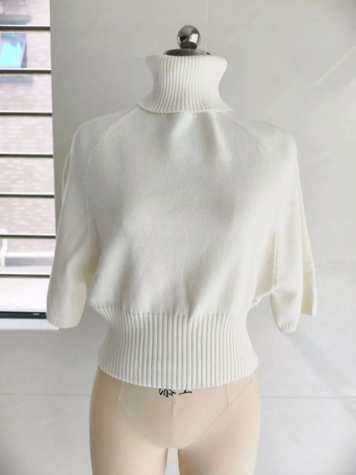 Turtleneck batwing top, cream mannequin front
