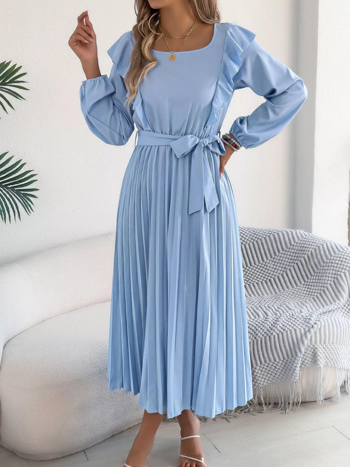 Blue ruffled pleated tie-waist midi dress, front with hand at waist.