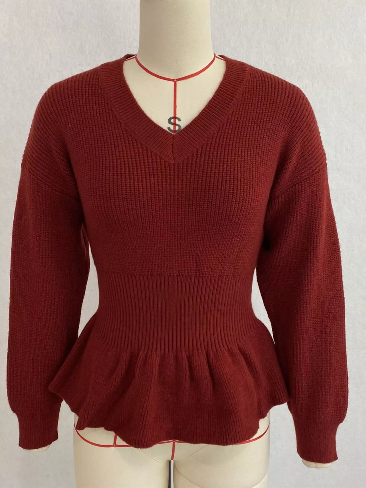Rust v-neck peplum-hem knit sweater, front on dress form.