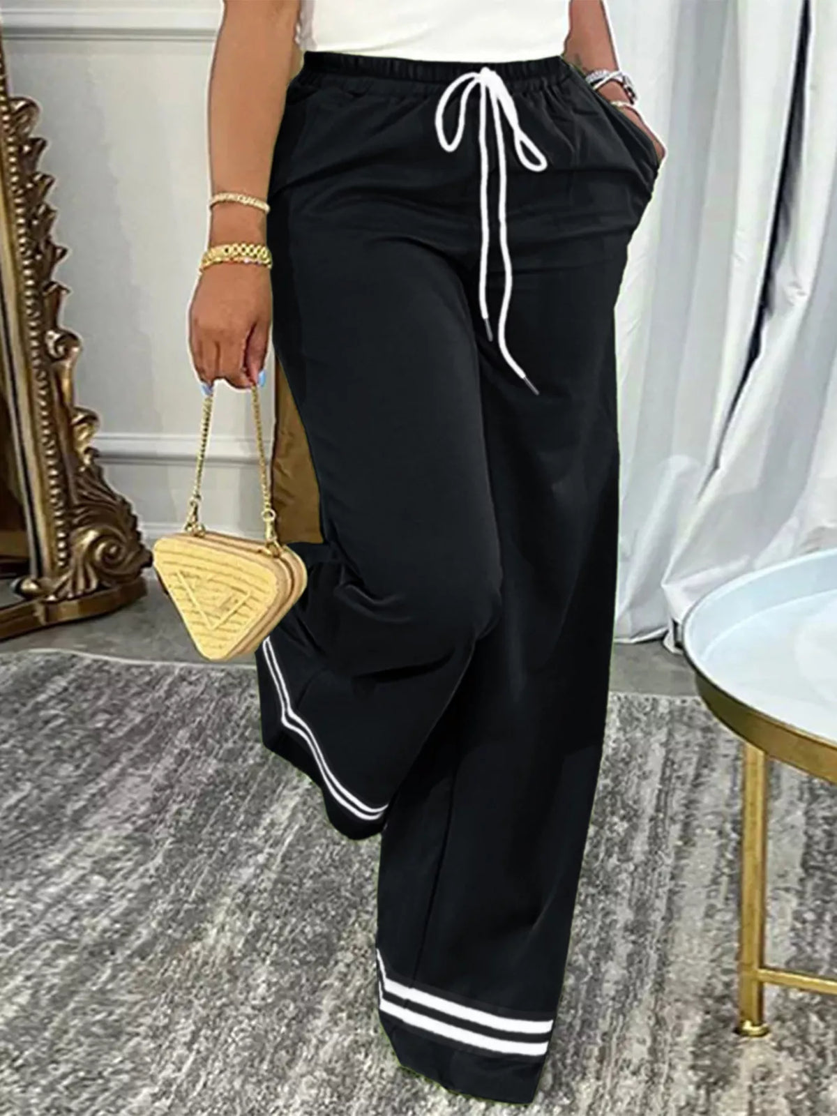 Black and white wide-leg pants with striped hems, front view with bent leg