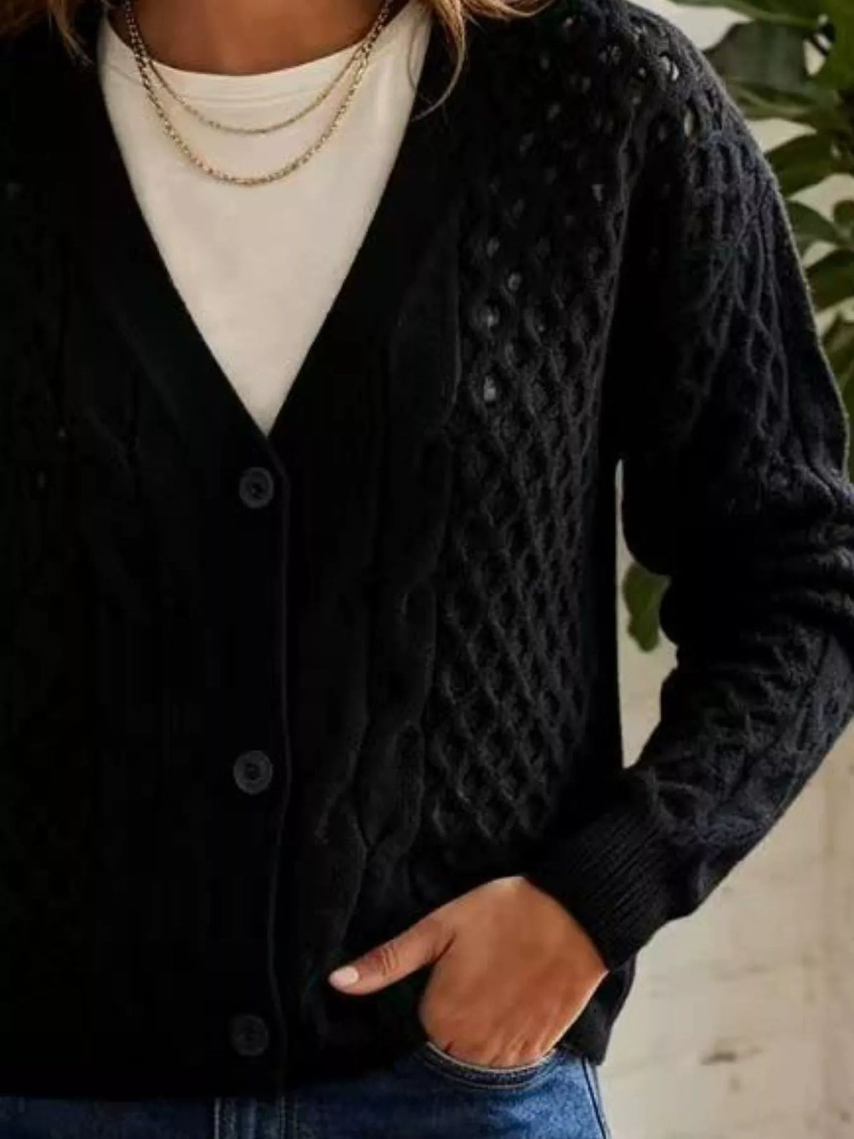 Black cable-knit v-neck button-front cardigan, cable knit and button detail.