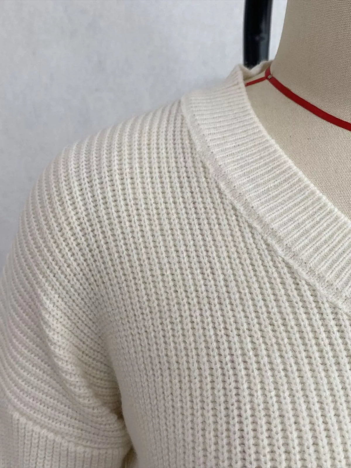Ivory v-neck peplum-hem knit sweater, neckline and knit detail.