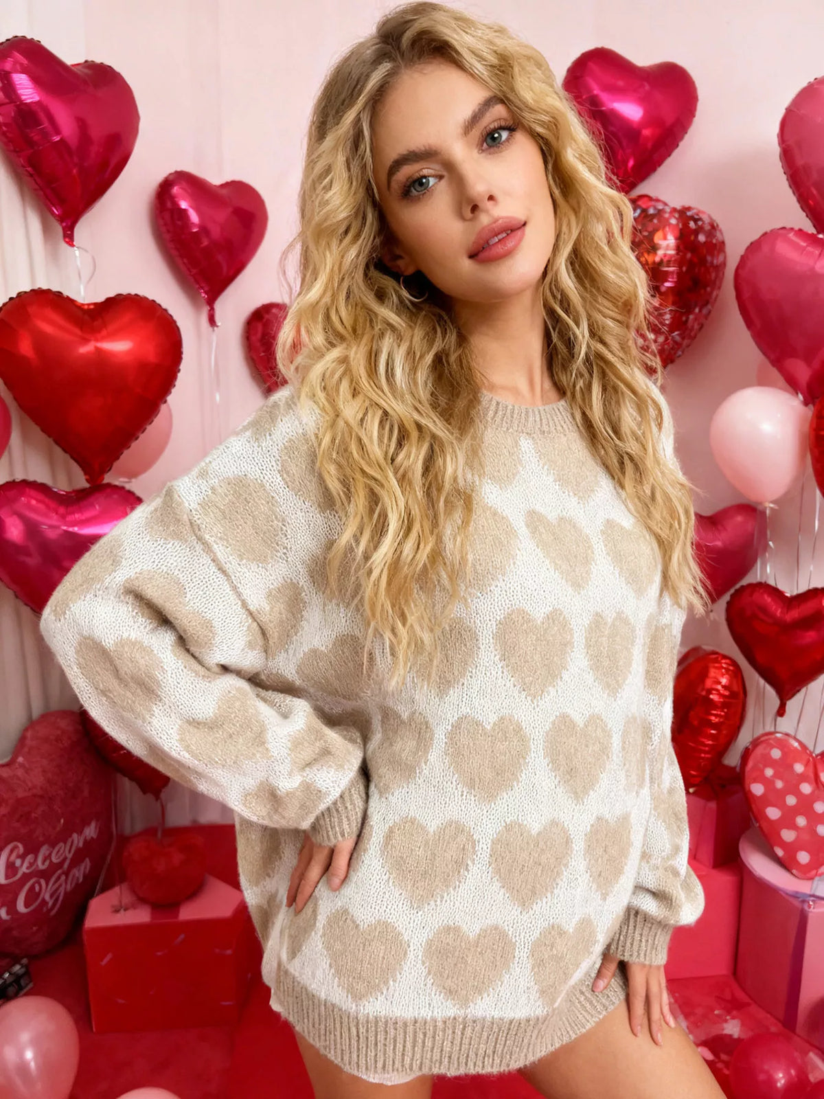 Cream and beige allover heart dropped-shoulder sweater, front with hand at hip.