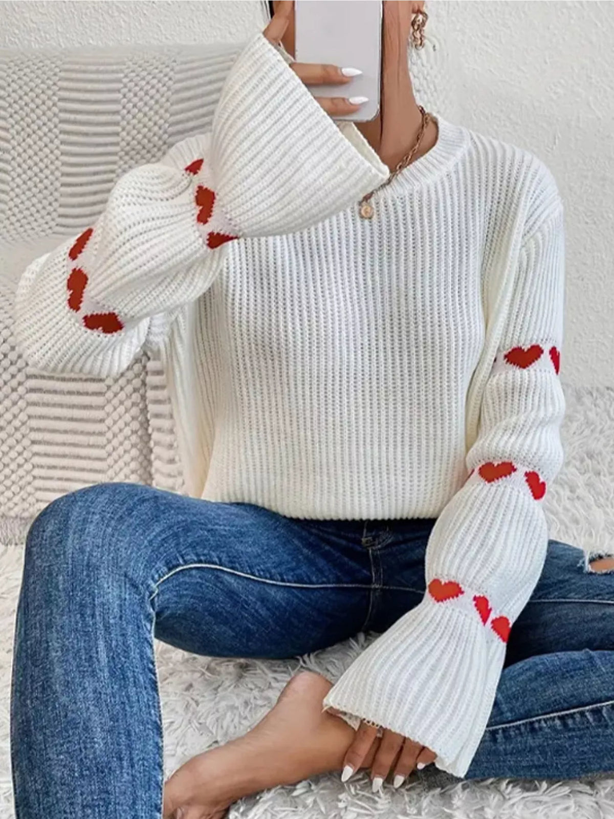 White and red heart-sleeve dropped-shoulder sweater, seated front view.
