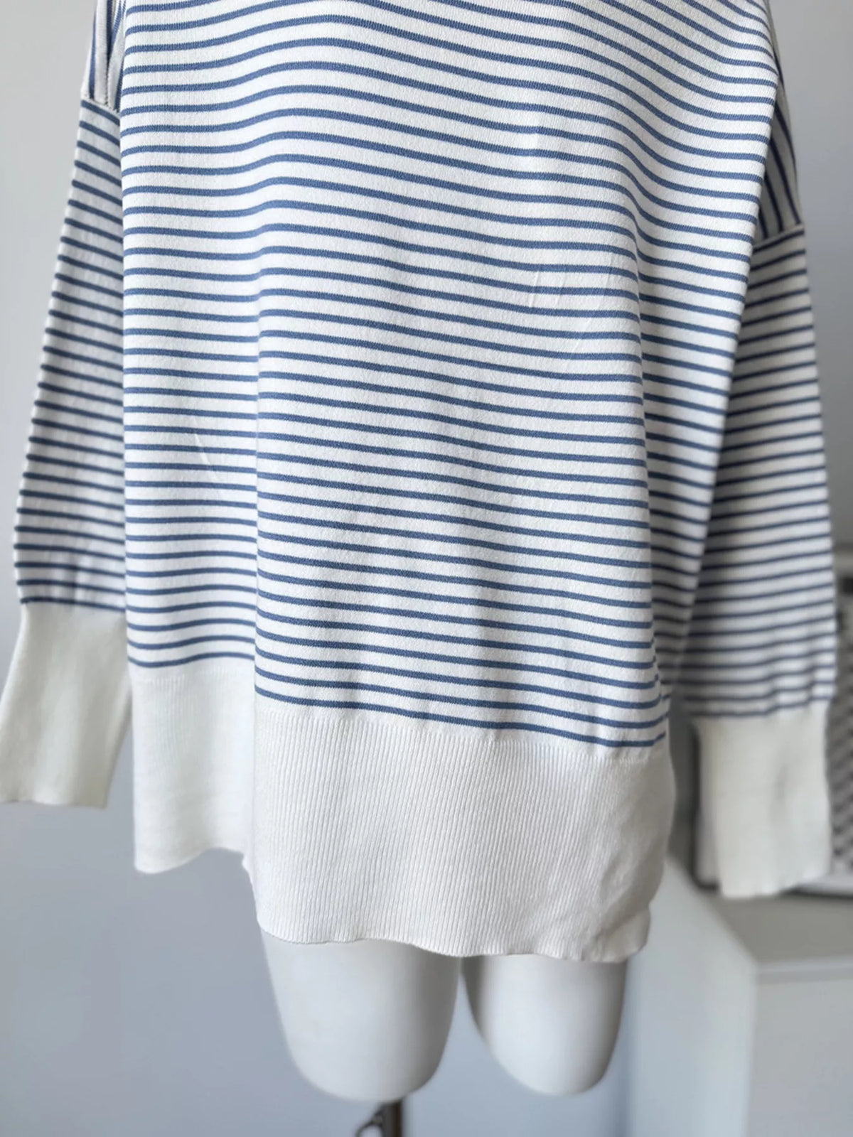 Striped round-neck knit top in white and blue, hem detail