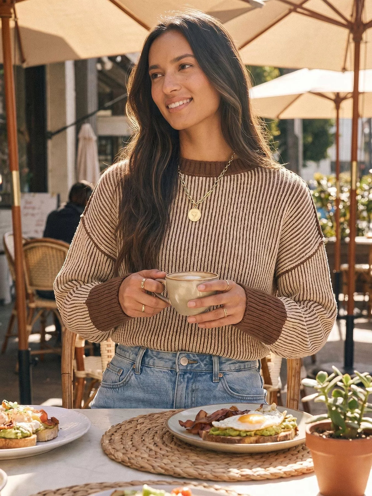 Beige and brown ribbed side-slit sweater with contrast trim, front tucked into jeans.