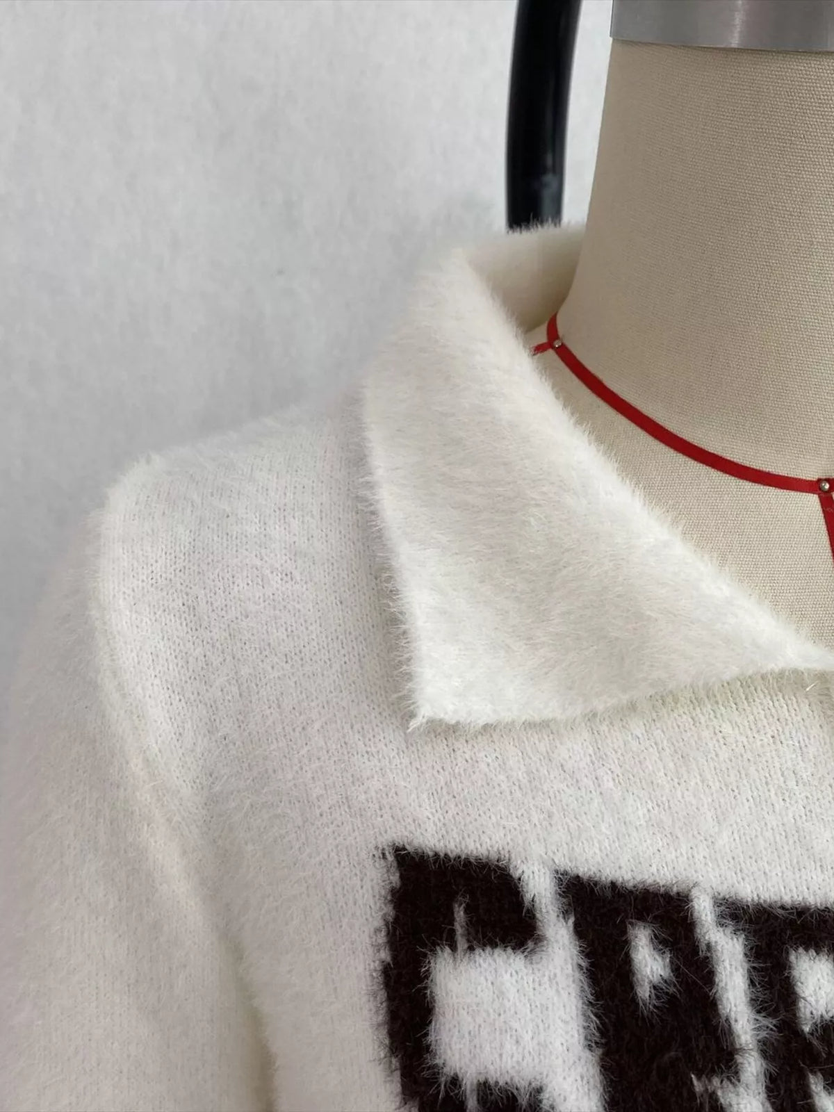 White fuzzy letter zip-up cardigan, collar and lettering detail.