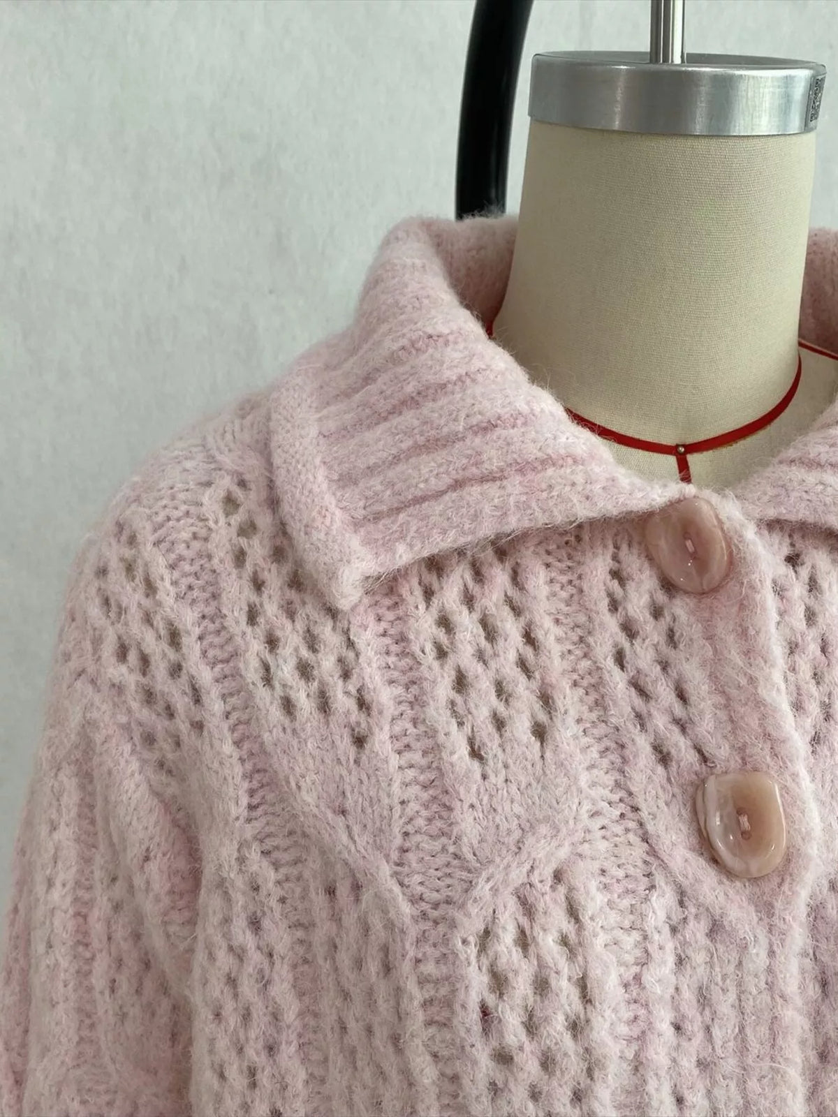 Pink cable-knit collared button-front cardigan, collar and cable-knit detail.