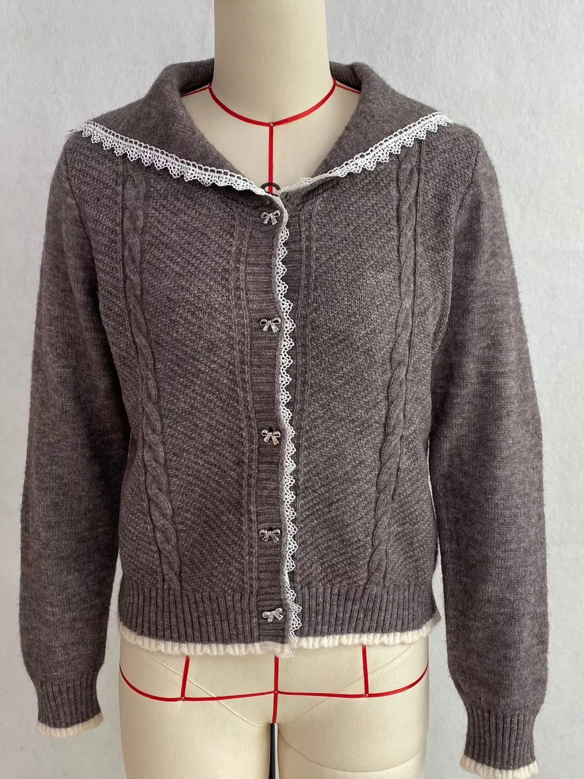 Charcoal cable-knit cardigan with lace trim, front on dress form.