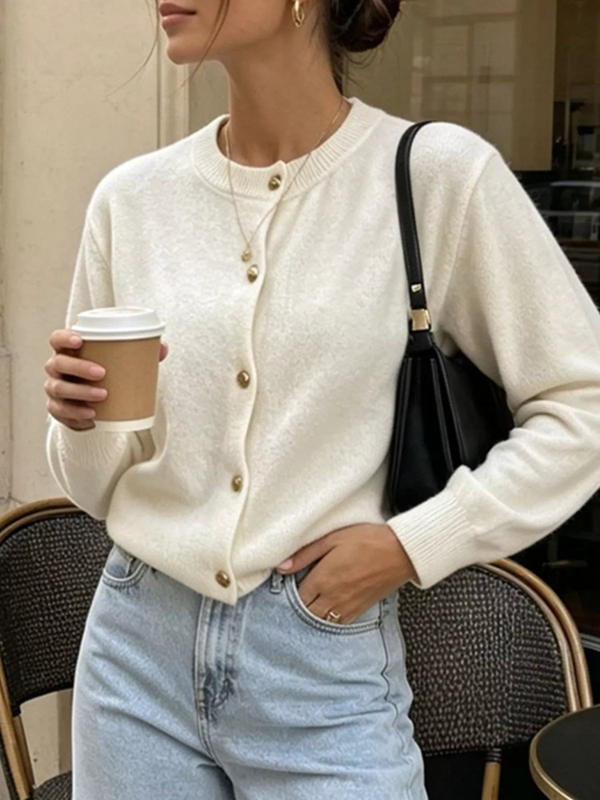 White round-neck button-front knit cardigan, seated front view.
