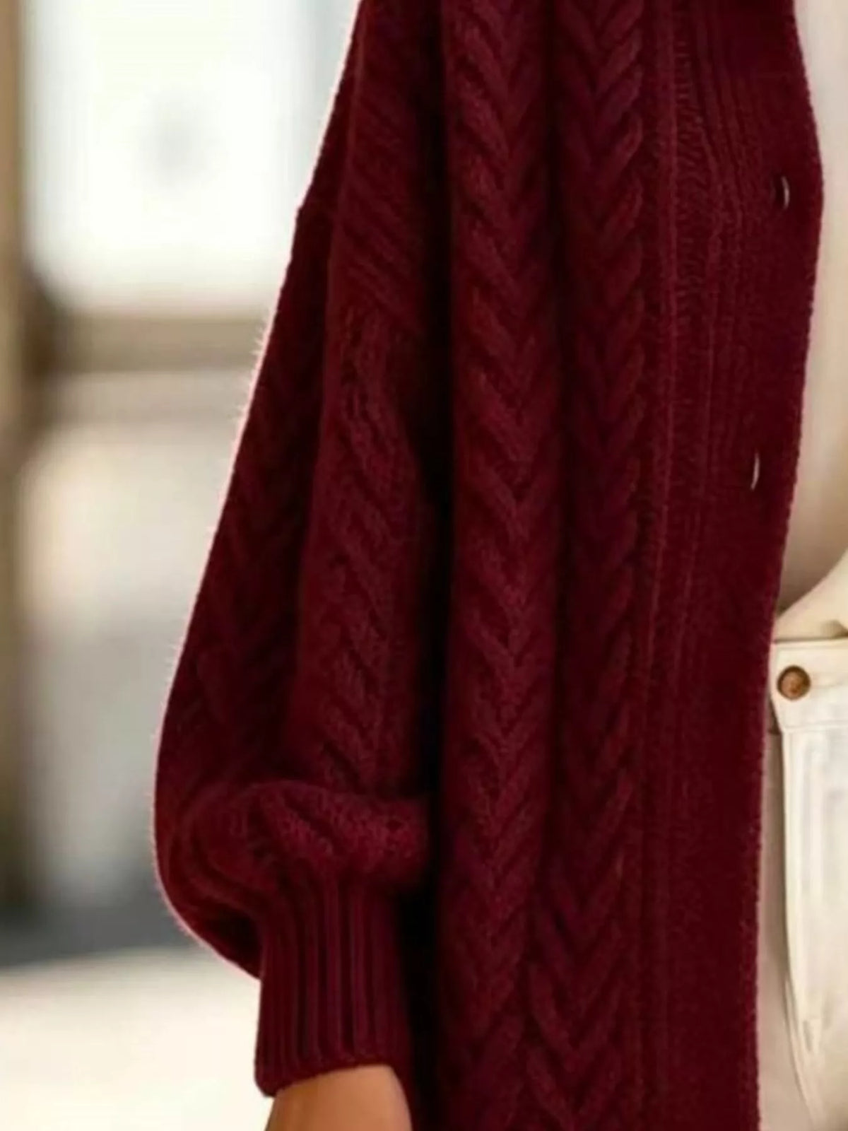 Burgundy longline cable-knit button-front cardigan, sleeve and cable knit detail.