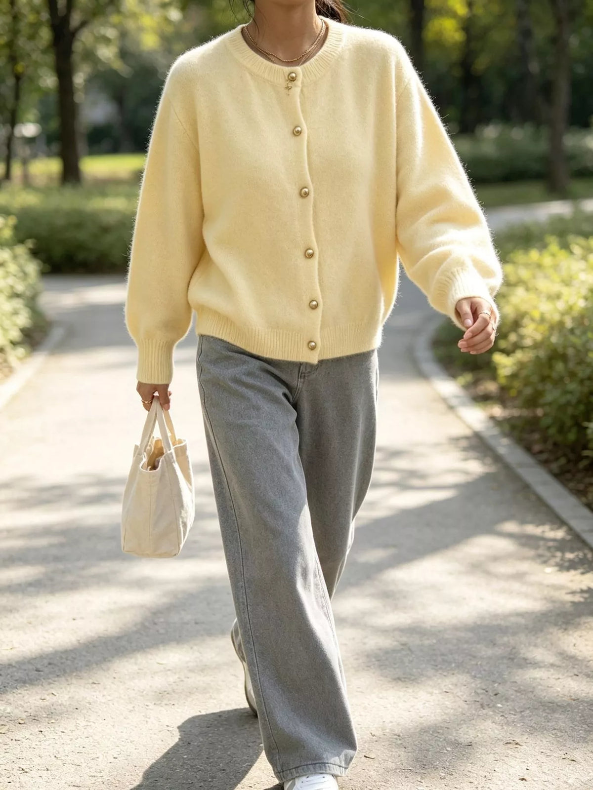 Pale yellow round-neck button-front knit cardigan, walking front view.