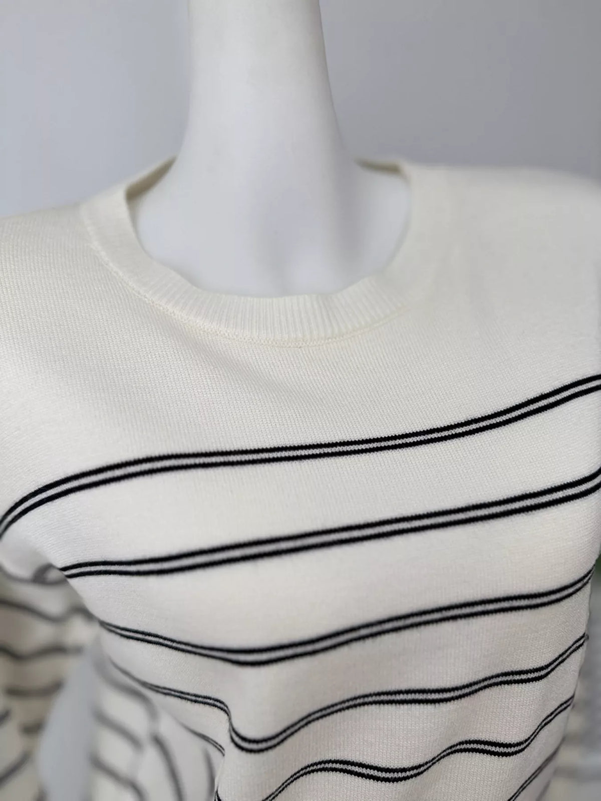 Striped crewneck sweater with layered tie detail in white and black, neckline close-up