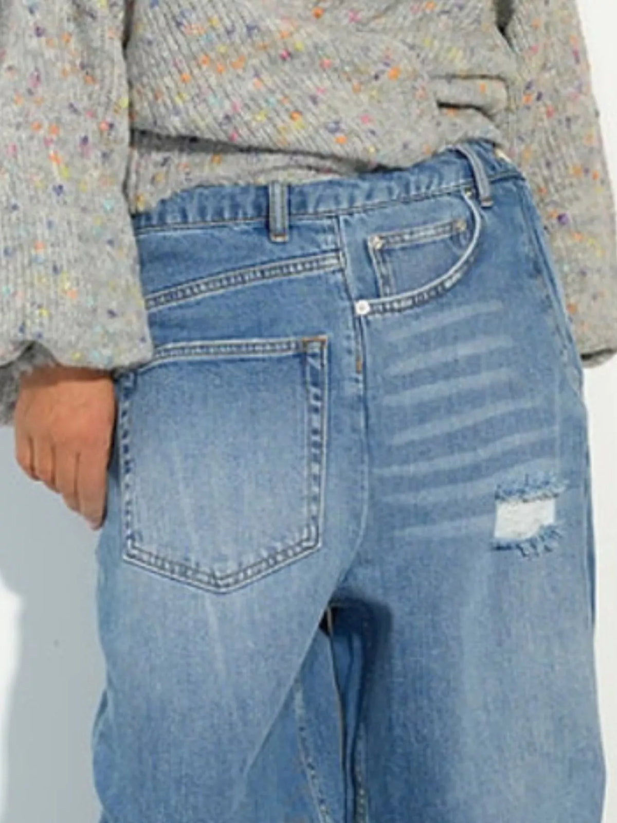 Blue high-waisted distressed wide-leg jeans, waist and front-pocket detail.