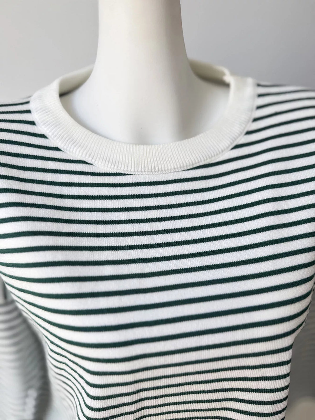 Striped round-neck knit top in white and green, neckline detail