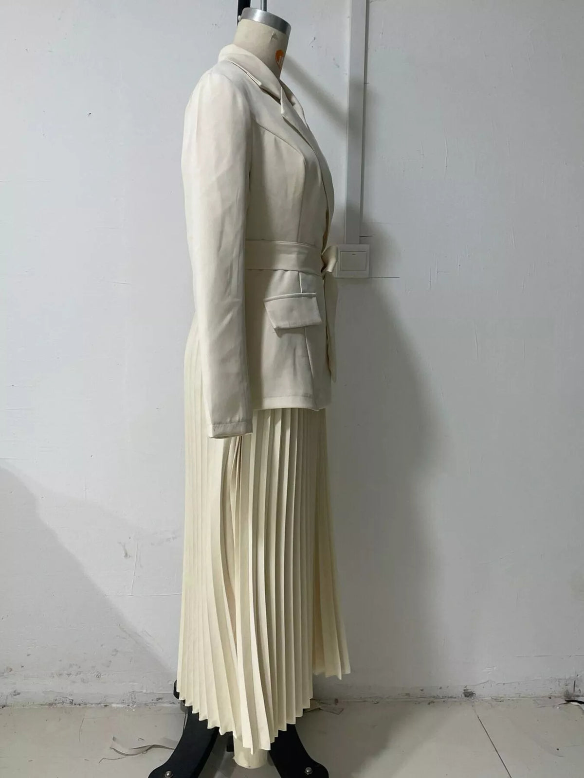Beige belted blazer-style pleated midi dress, side on dress form