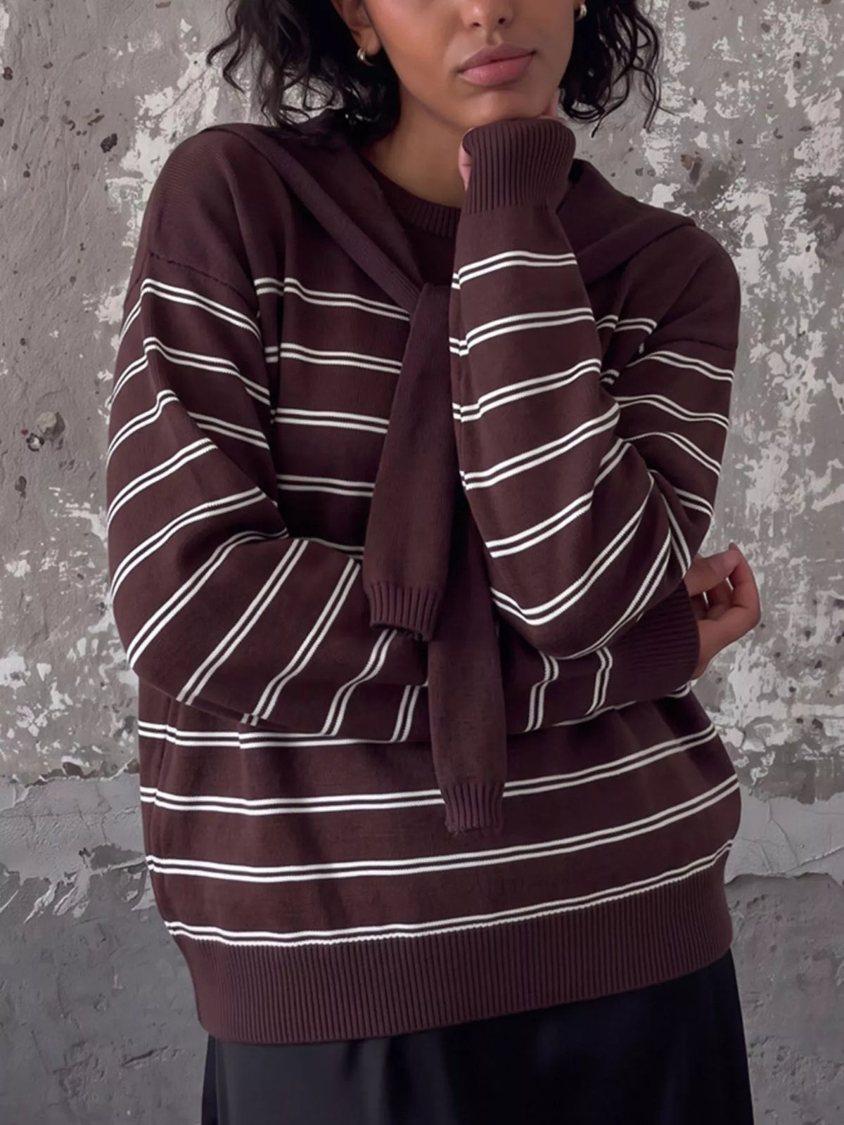 Striped crewneck sweater with layered tie detail in brown, crossed-arm front view
