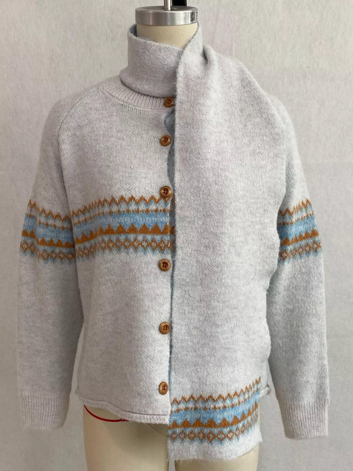 Light gray geometric button-front knit cardigan, front on dress form with scarf.