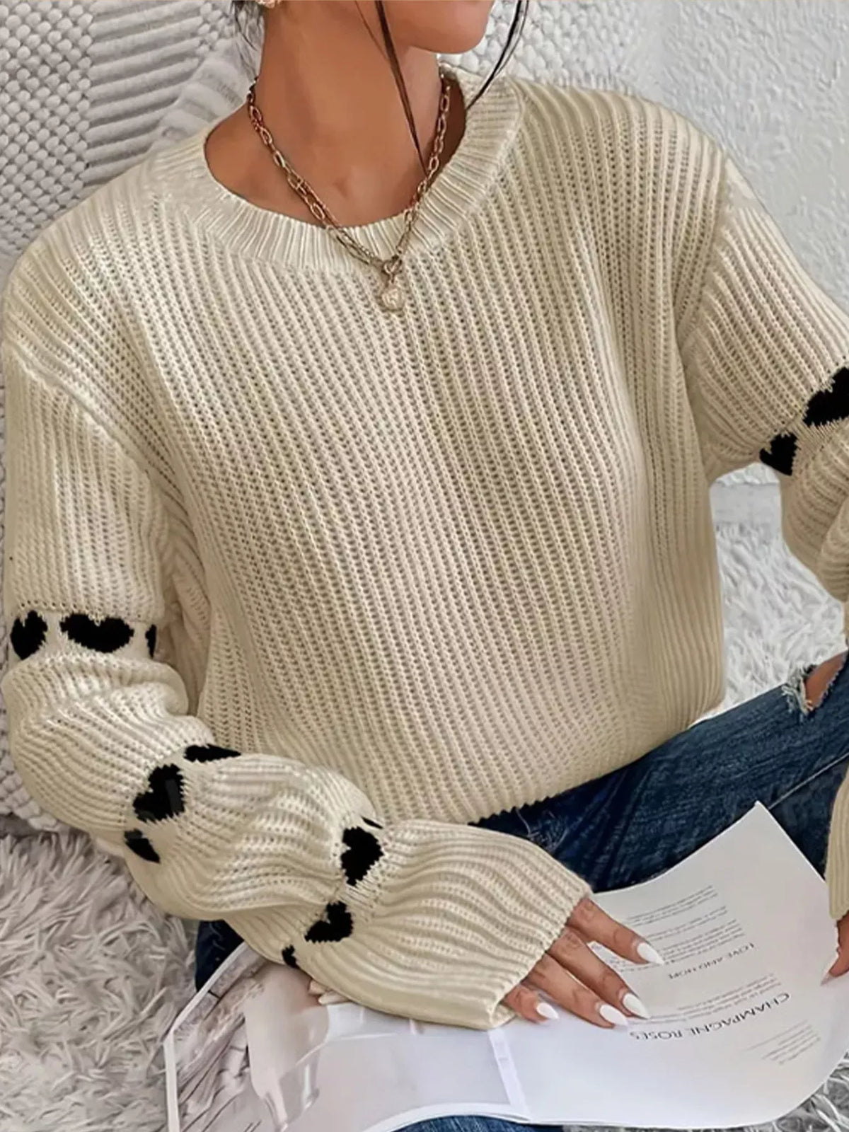 Beige and black heart-sleeve dropped-shoulder sweater, sleeve and rib-knit detail.