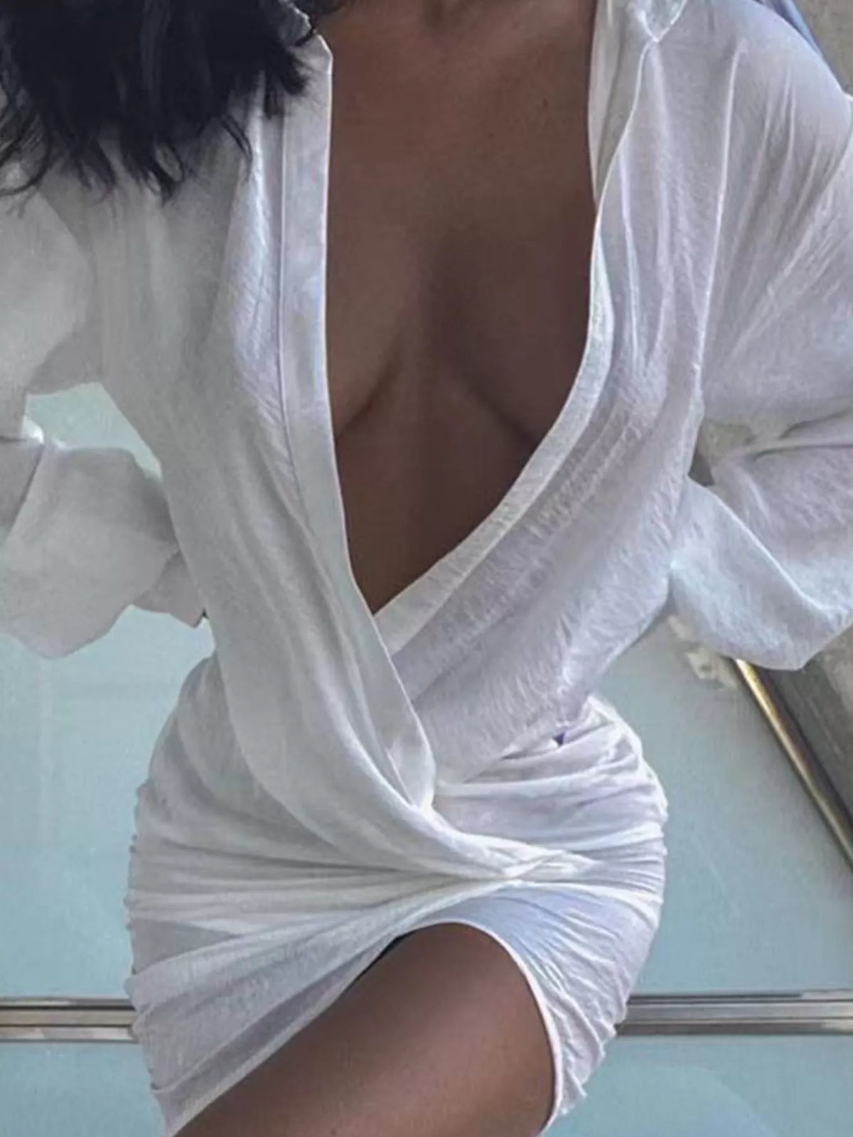 White deep v-neck ruched asymmetric mini dress, seated front view.