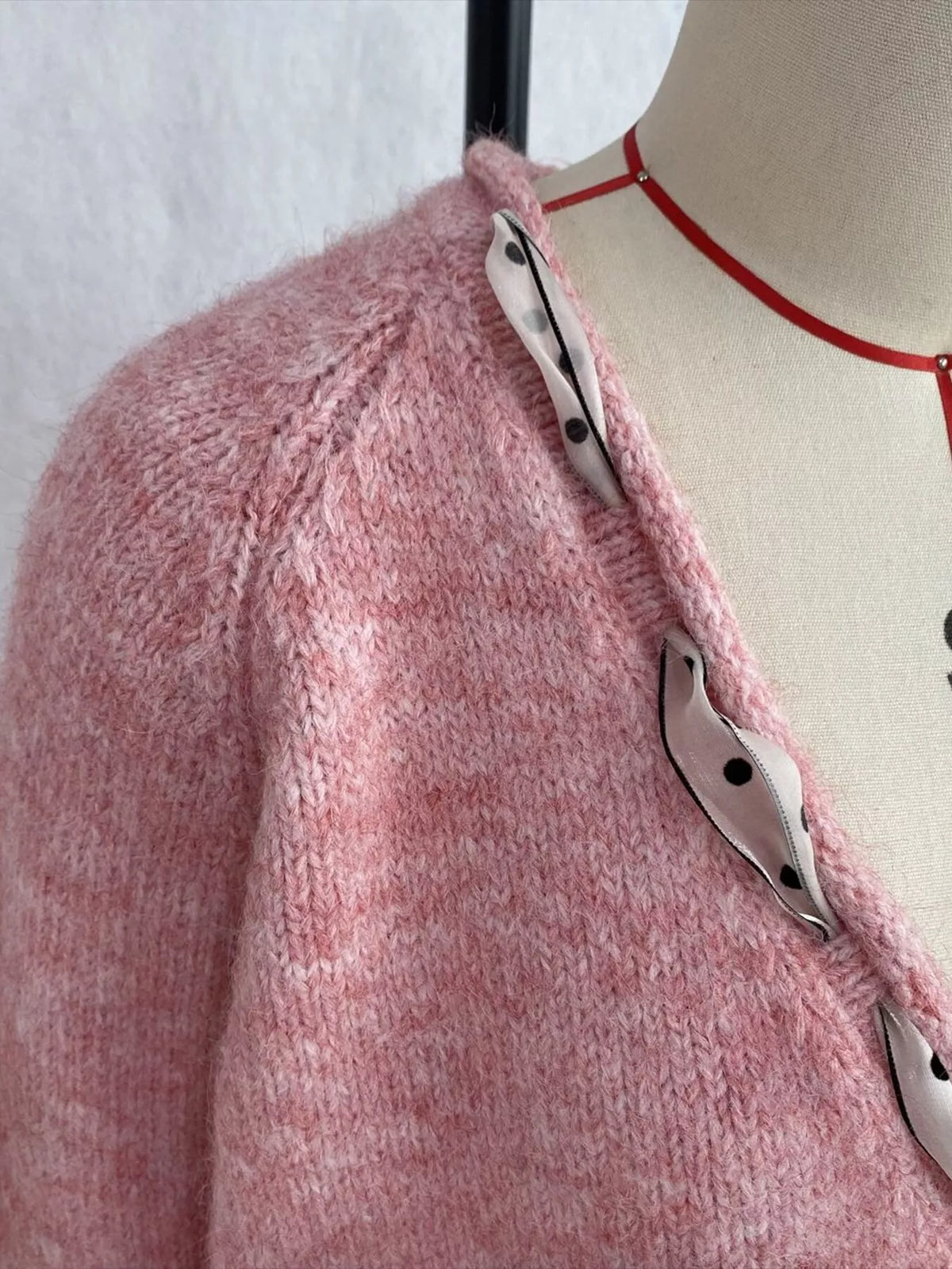 Pink v-neck knit top with polka dot ribbon tie, neckline and ribbon detail.