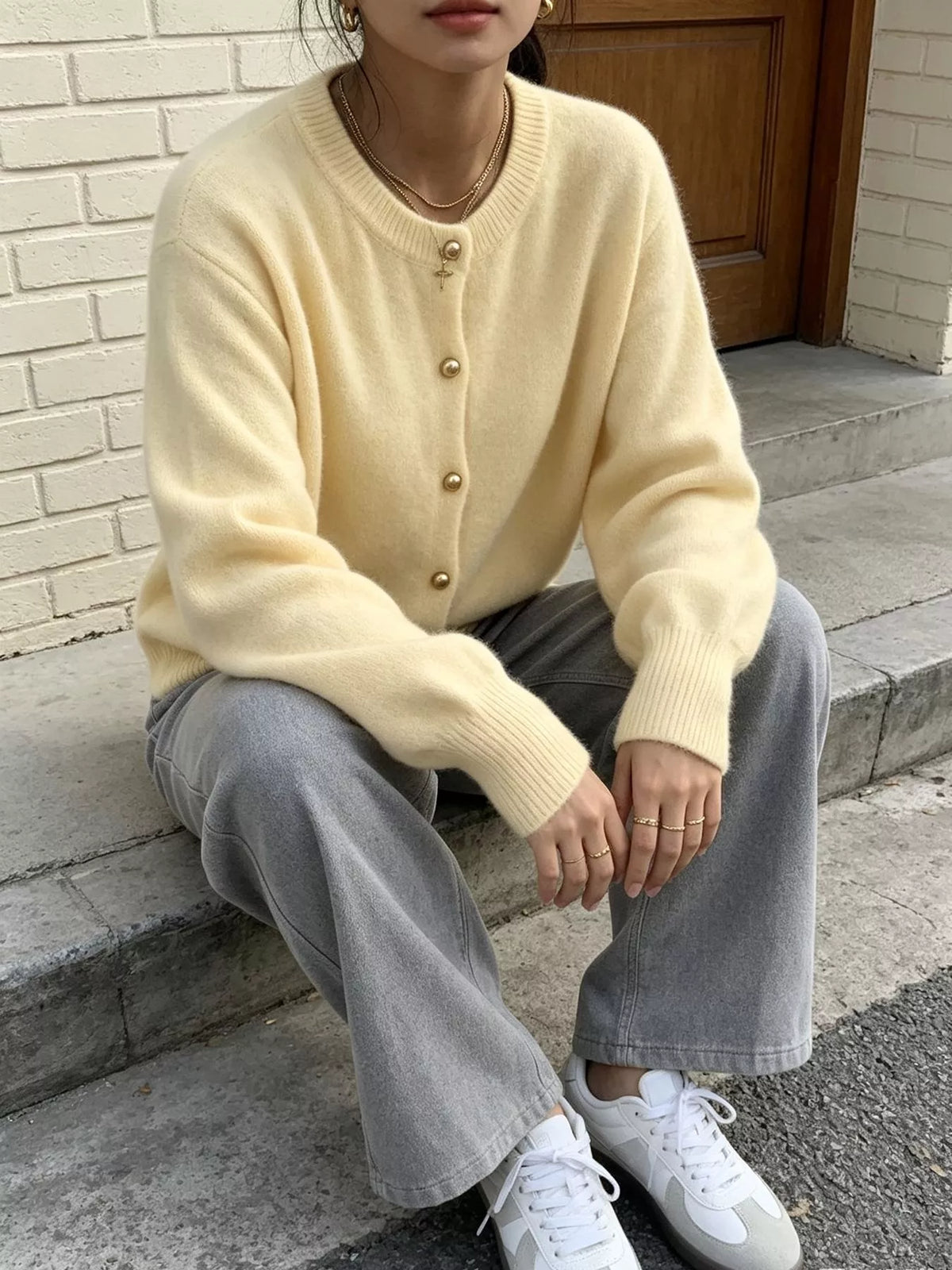 Pale yellow round-neck button-front knit cardigan, seated front view.