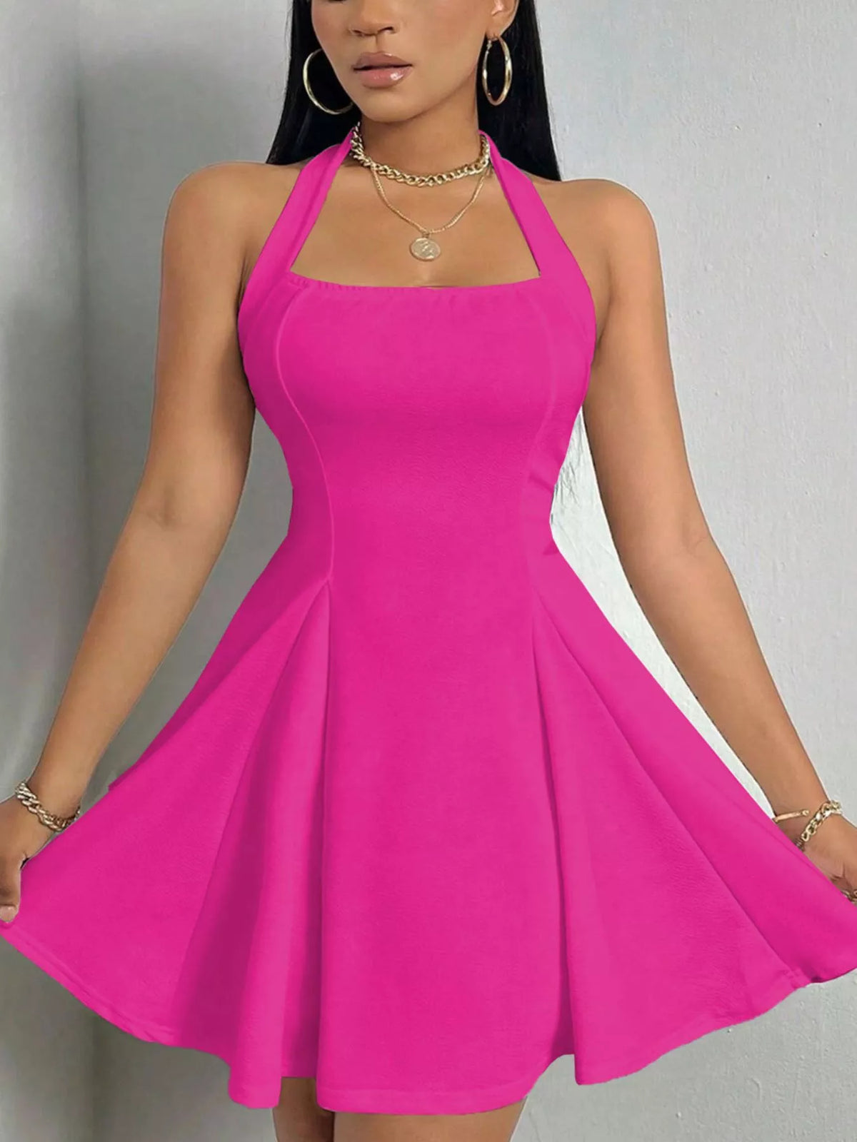 Fuchsia halter-neck a-line mini dress, front holding skirt.