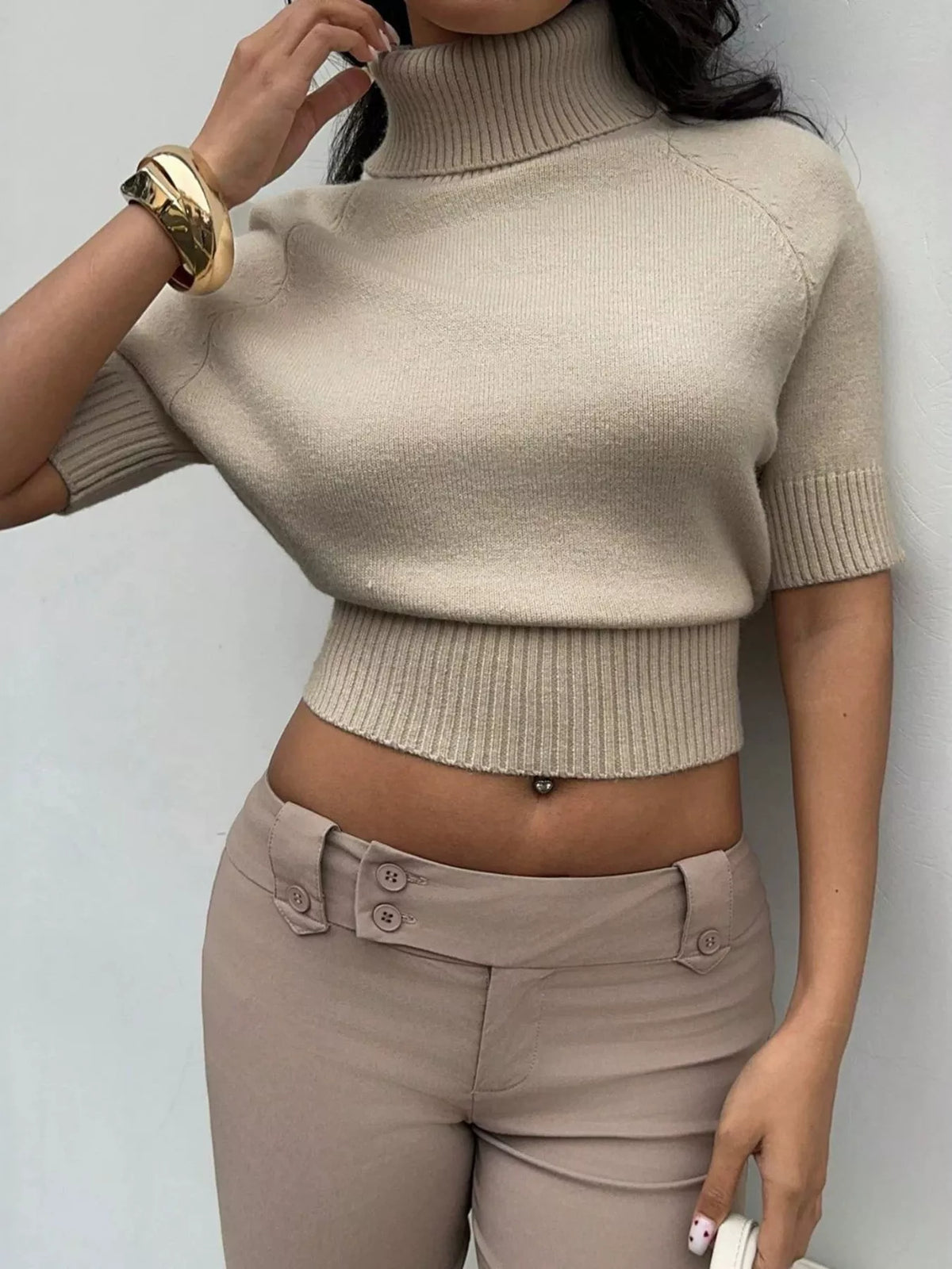 Beige turtleneck short-sleeve cropped sweater, front with raised hand.