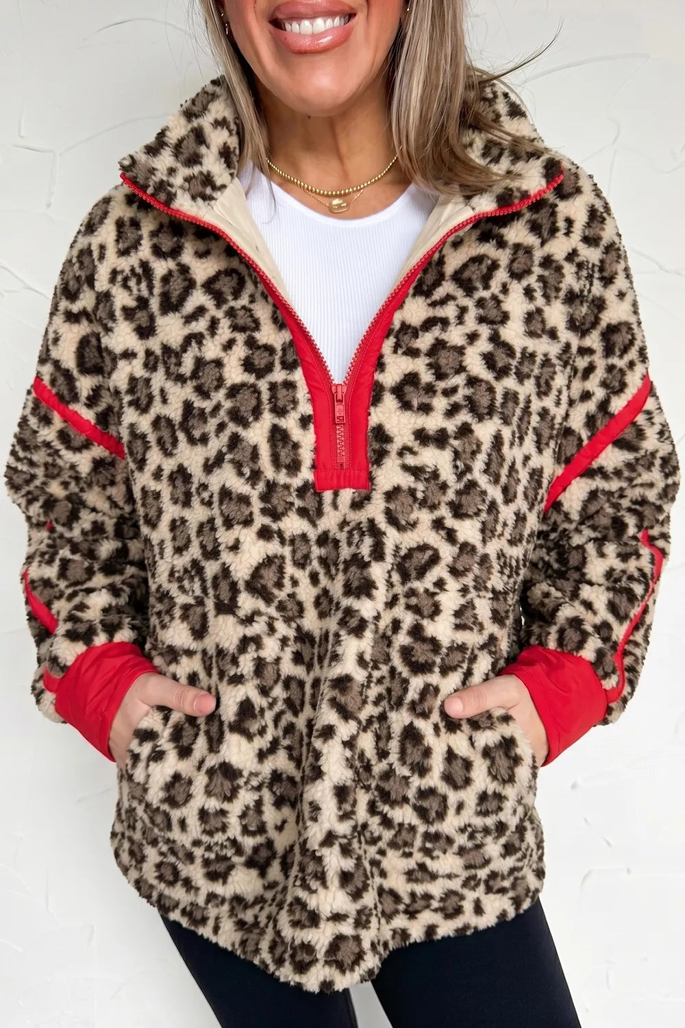 Leopard leopard half-zip sweatshirt with red trim, front with hands in pockets.