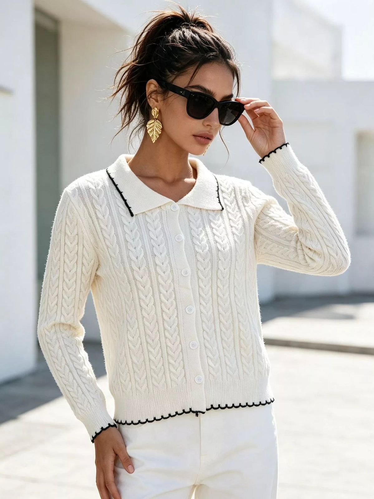 Ivory cable-knit polo-collar cardigan, front with raised hand.