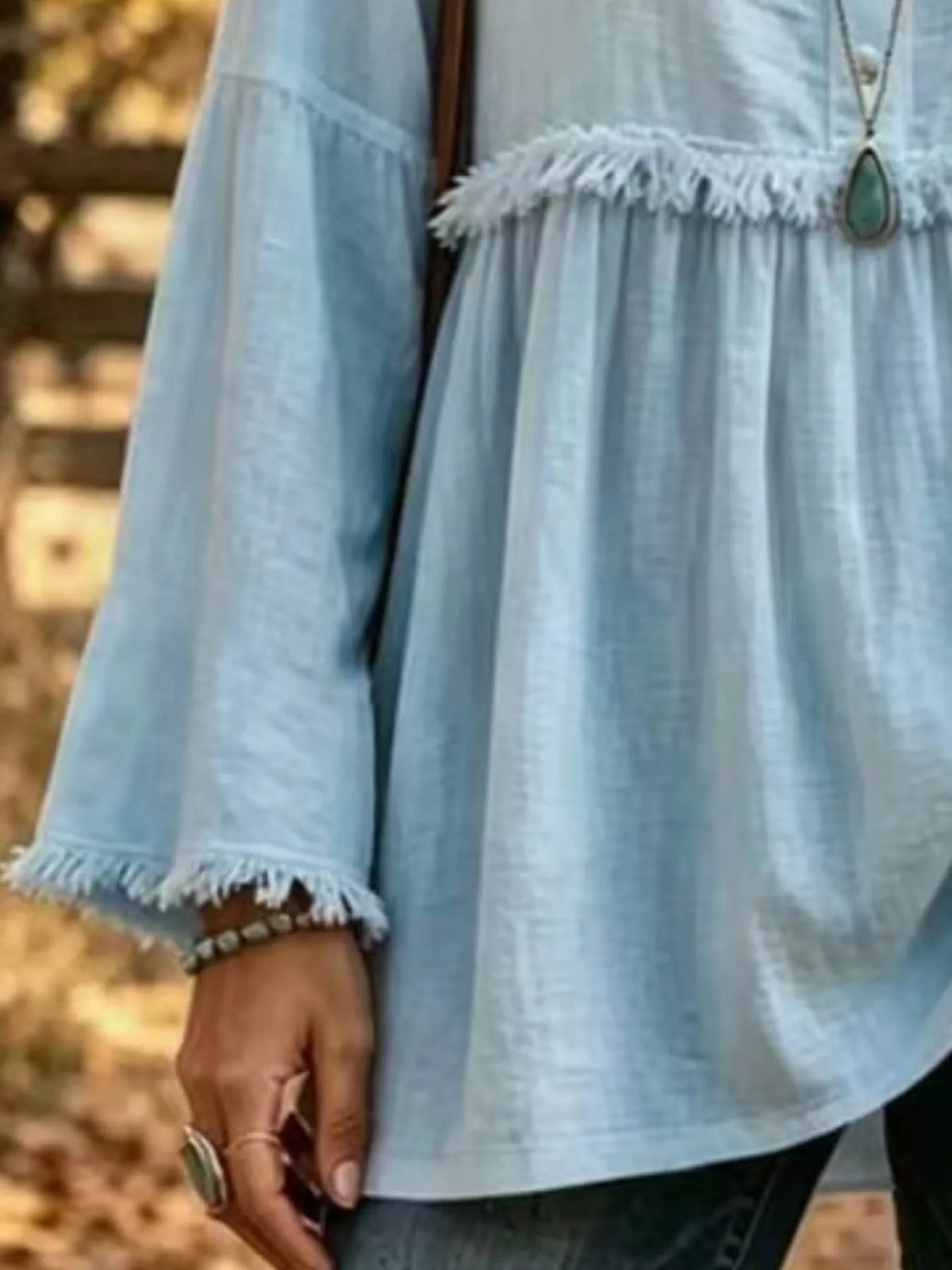 Blue fringed button detail blouse, frayed sleeve edge, waist seam, and flared hem