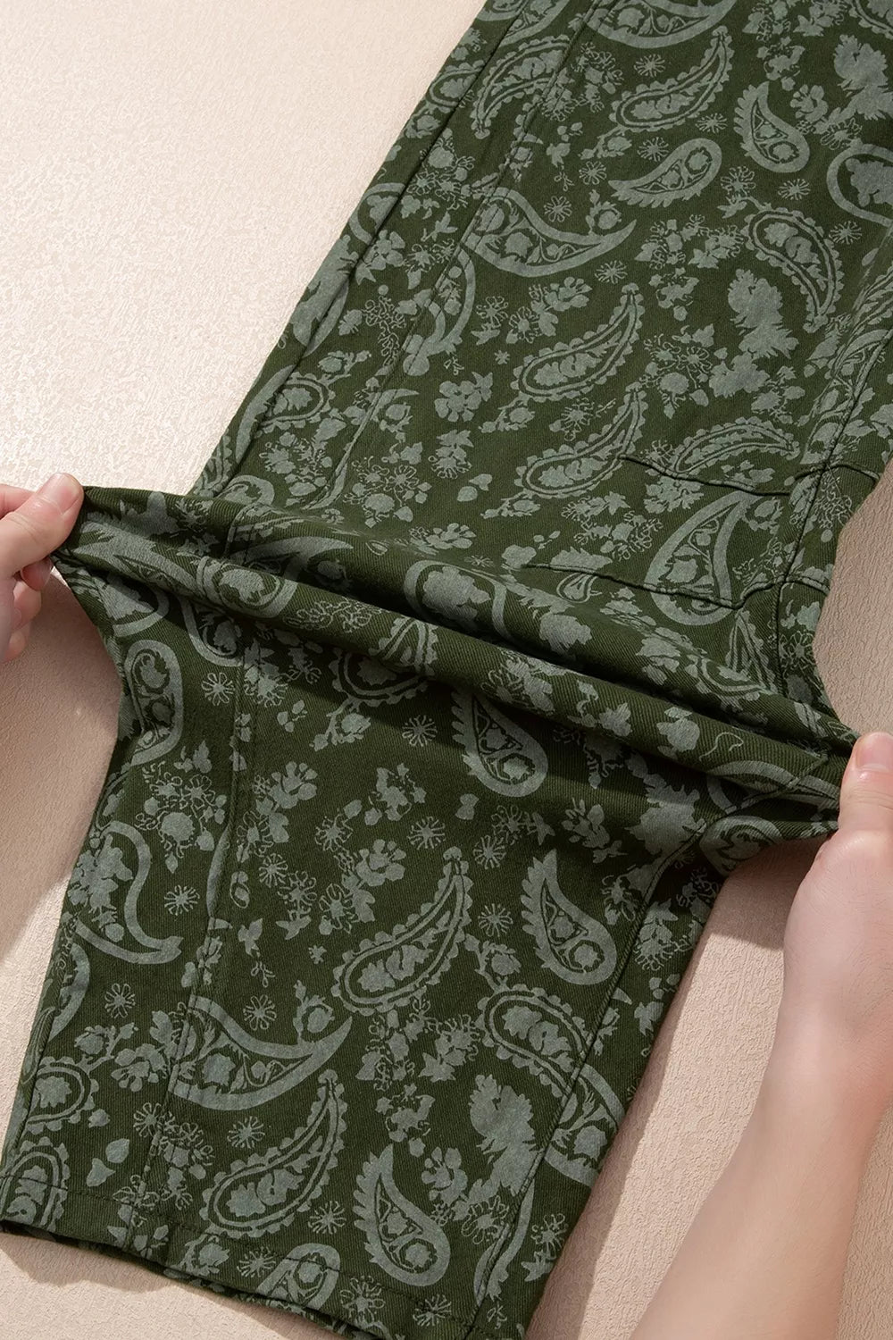 Green paisley print harem denim pants, leg fabric stretch demonstration