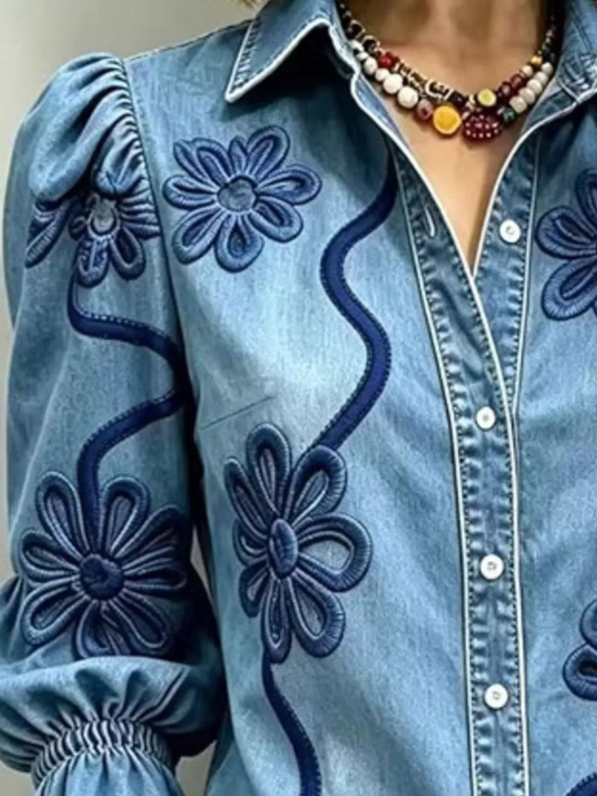 Blue floral-embroidered button-down shirt, floral embroidery detail.