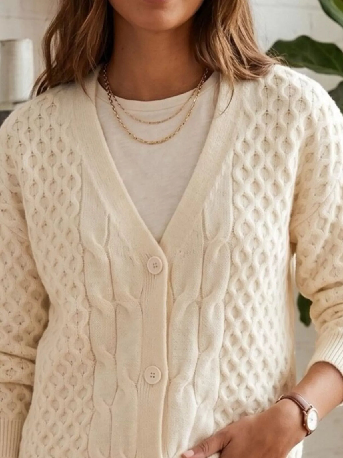 Ivory cable-knit v-neck button-front cardigan, cable knit and button detail.