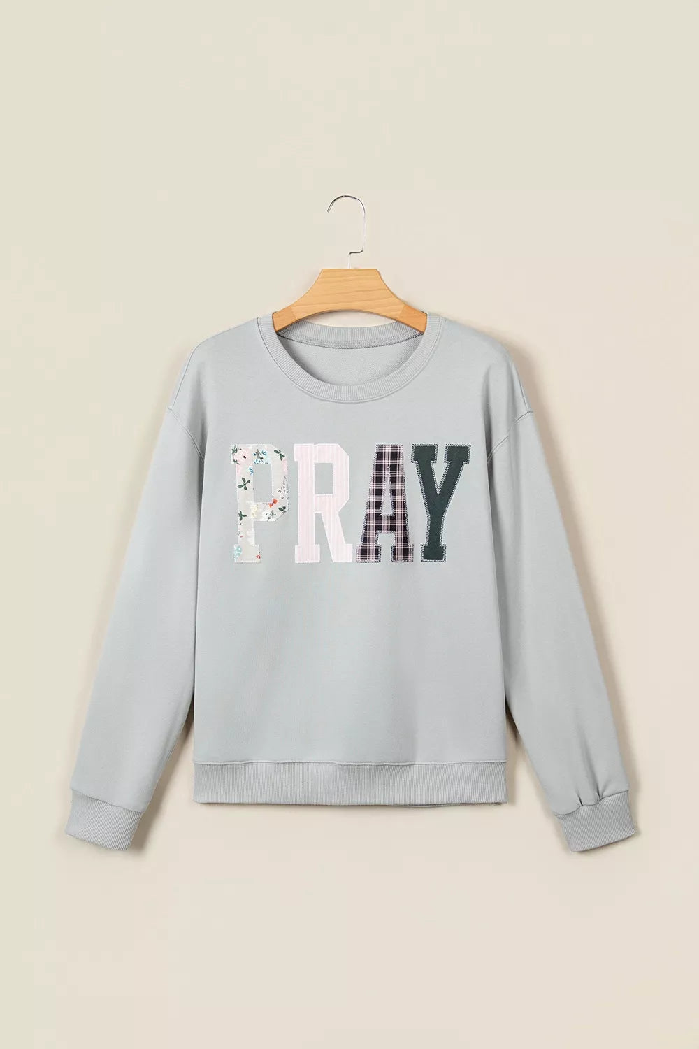 Gray floral and plaid PRAY patch sweatshirt, front on hanger