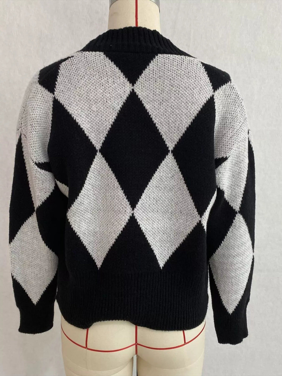 Black and white argyle v-neck button-front cardigan, back on dress form.