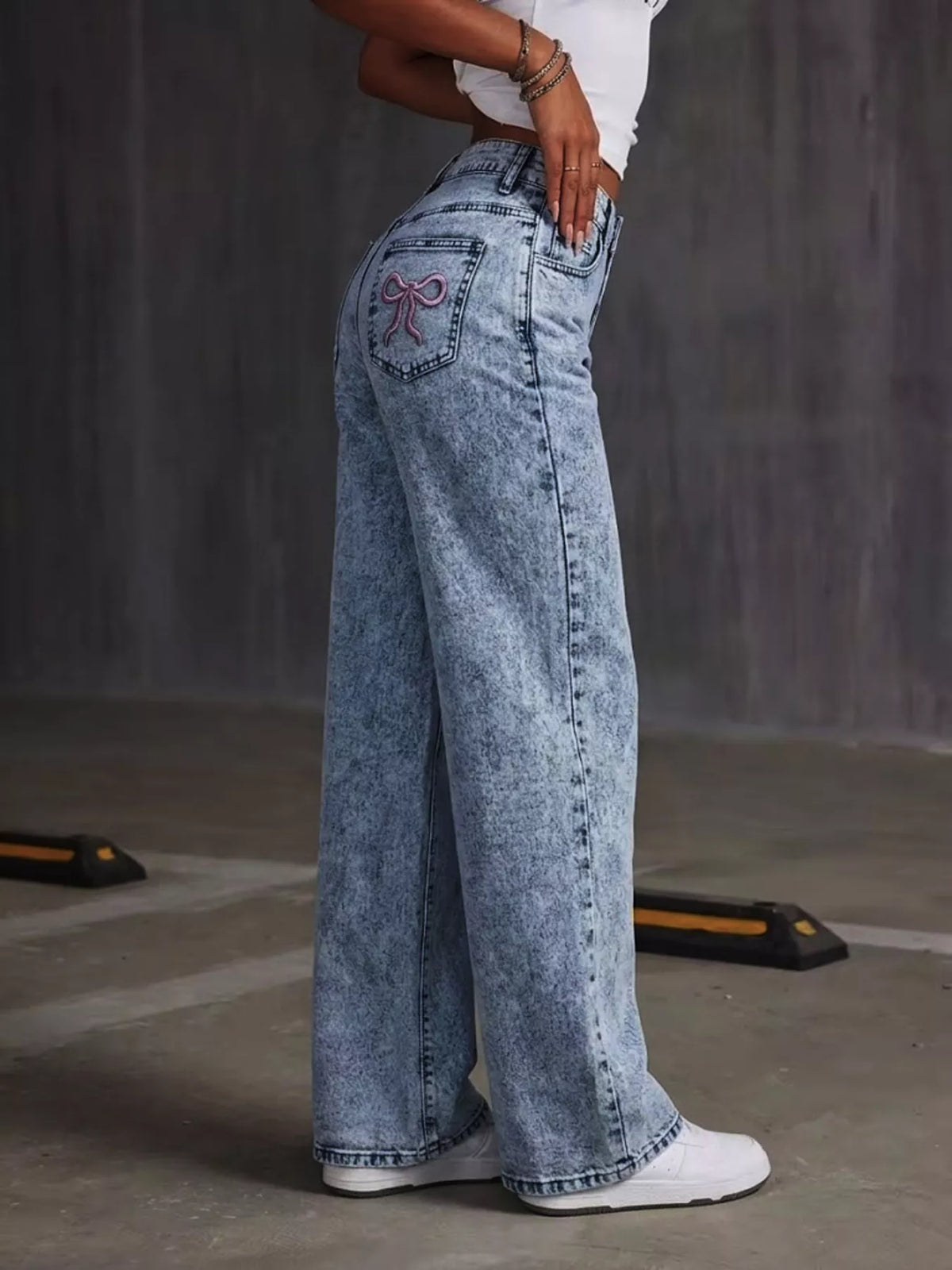 Blue bow-embroidered wide-leg jeans, side view.