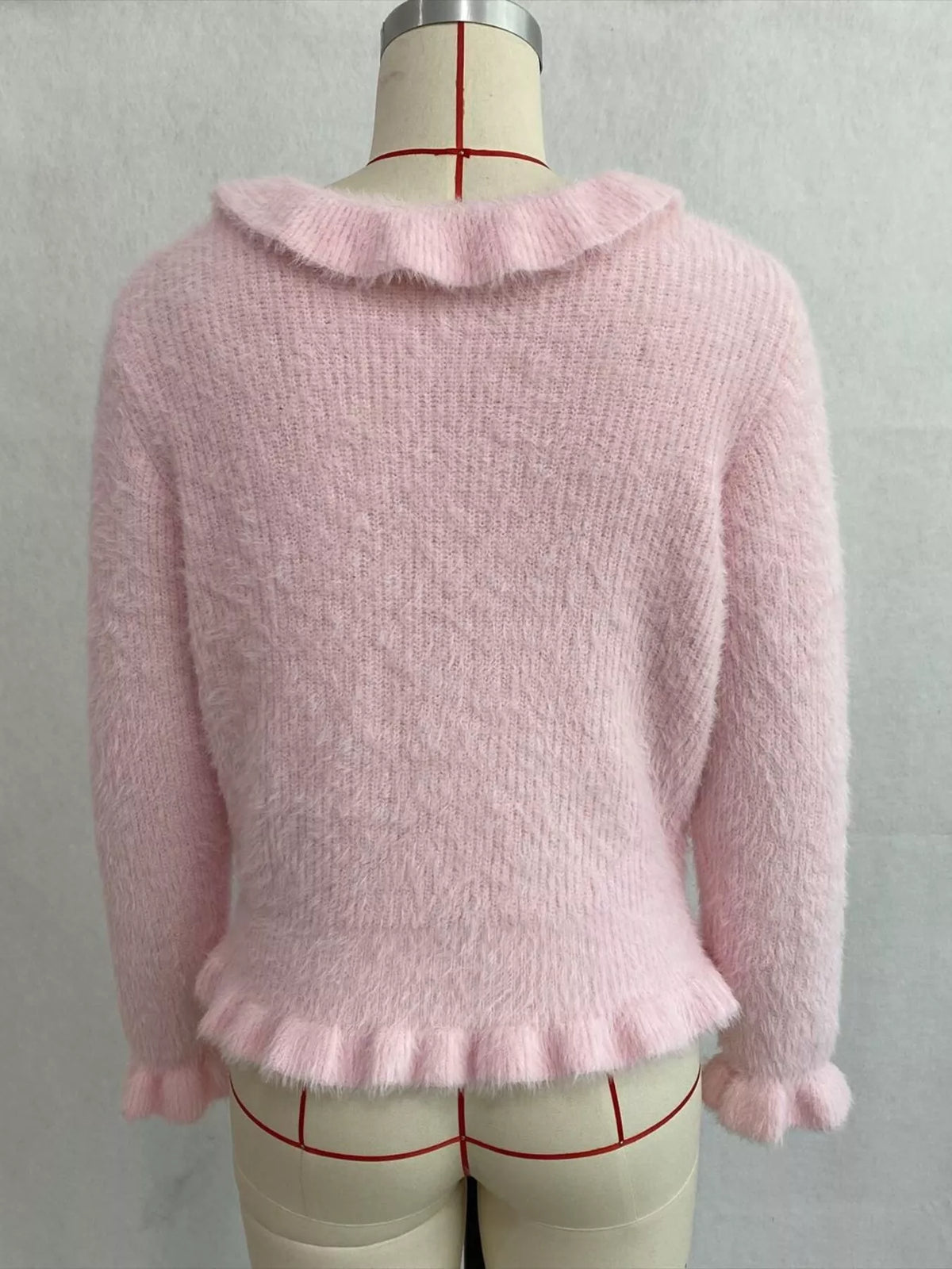 Pink fuzzy ruffle-trim button-front cardigan, back on dress form.