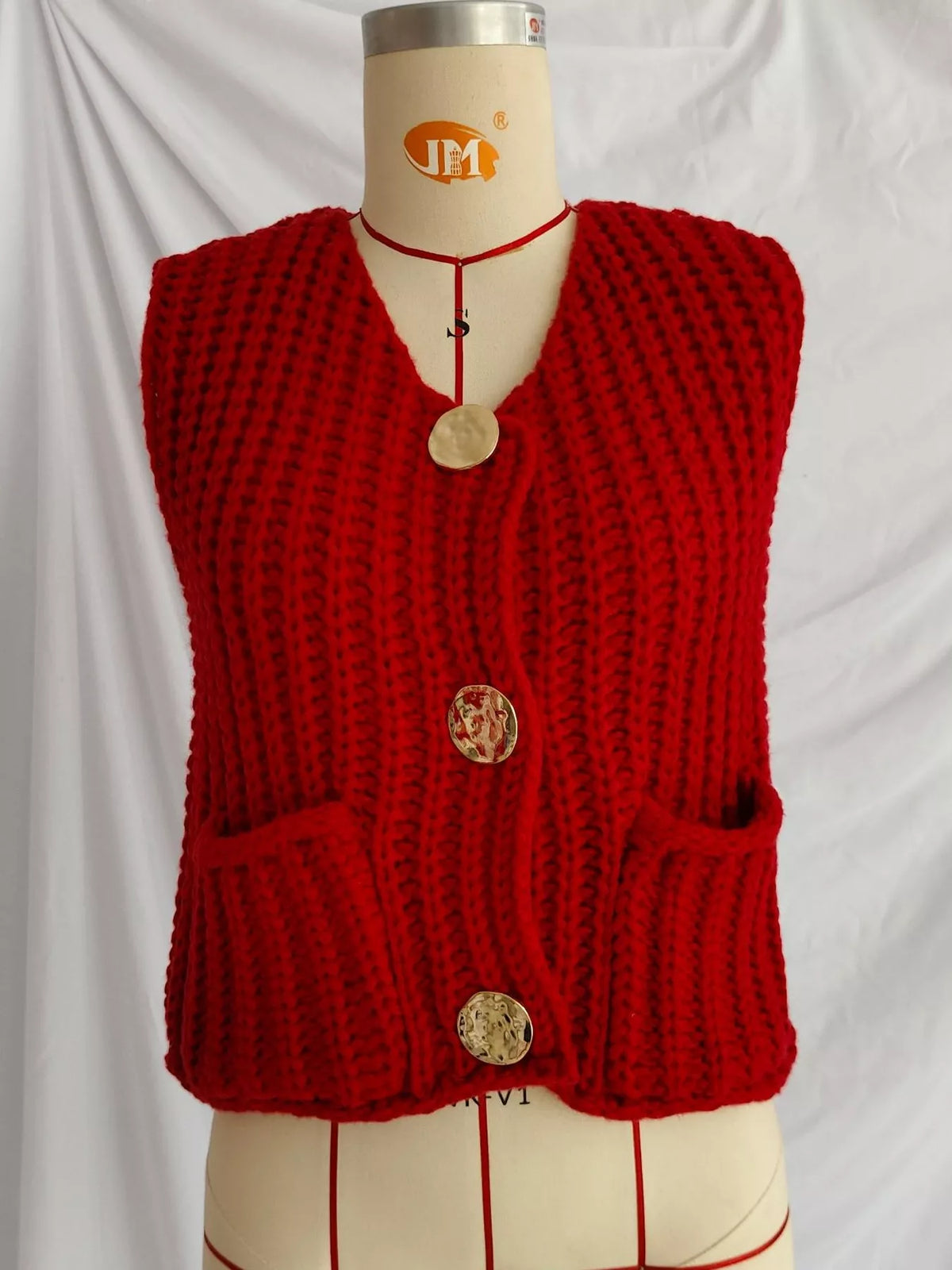Red button-front knit sweater vest, front on dress form.