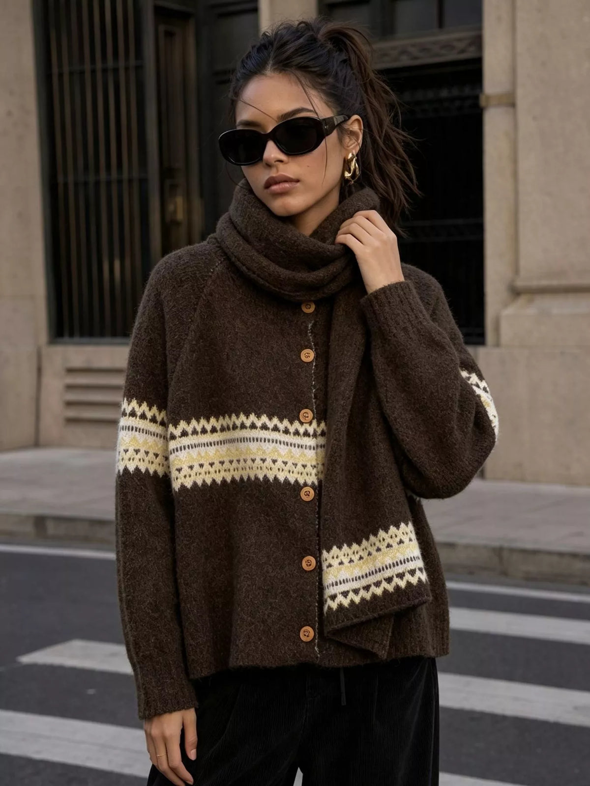 Brown geometric button-front knit cardigan, front view with raised hand.