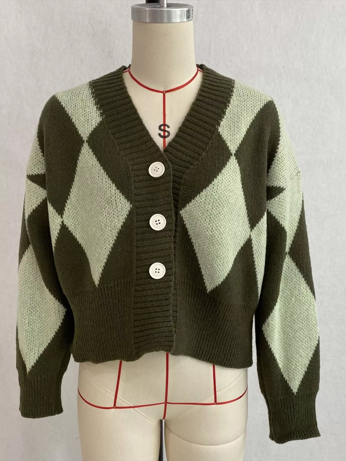 Green argyle v-neck button-front cardigan, front on dress form.