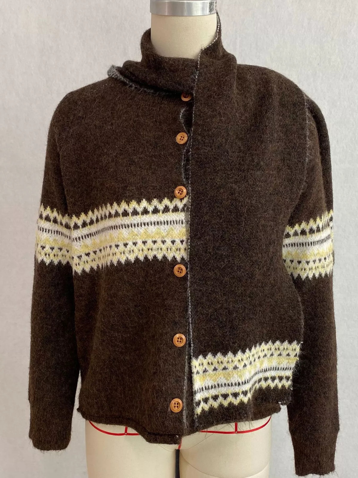 Brown geometric button-front knit cardigan, front on dress form with scarf.